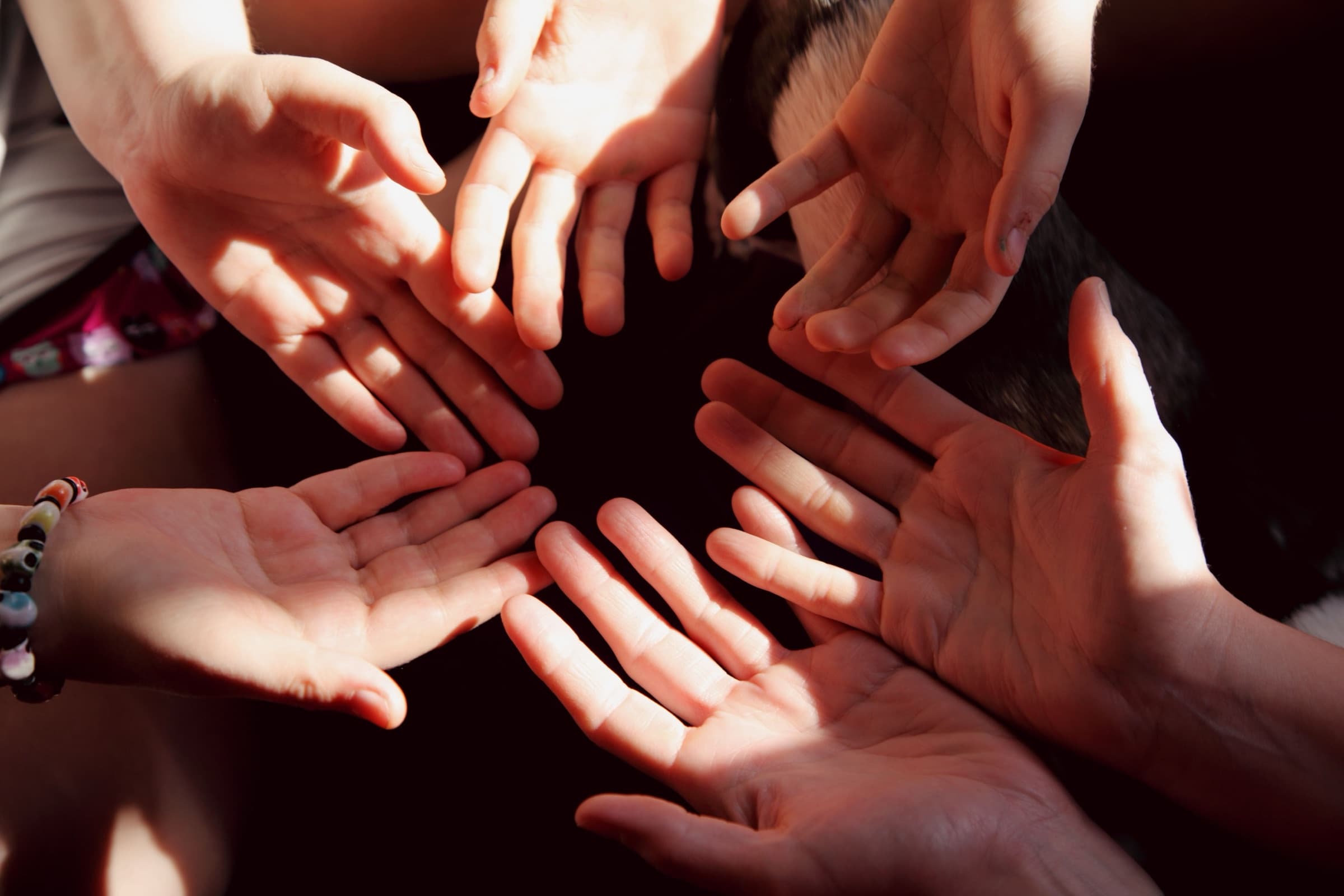 Manos abiertas de varias personas formando un círculo, unidas para ayudar